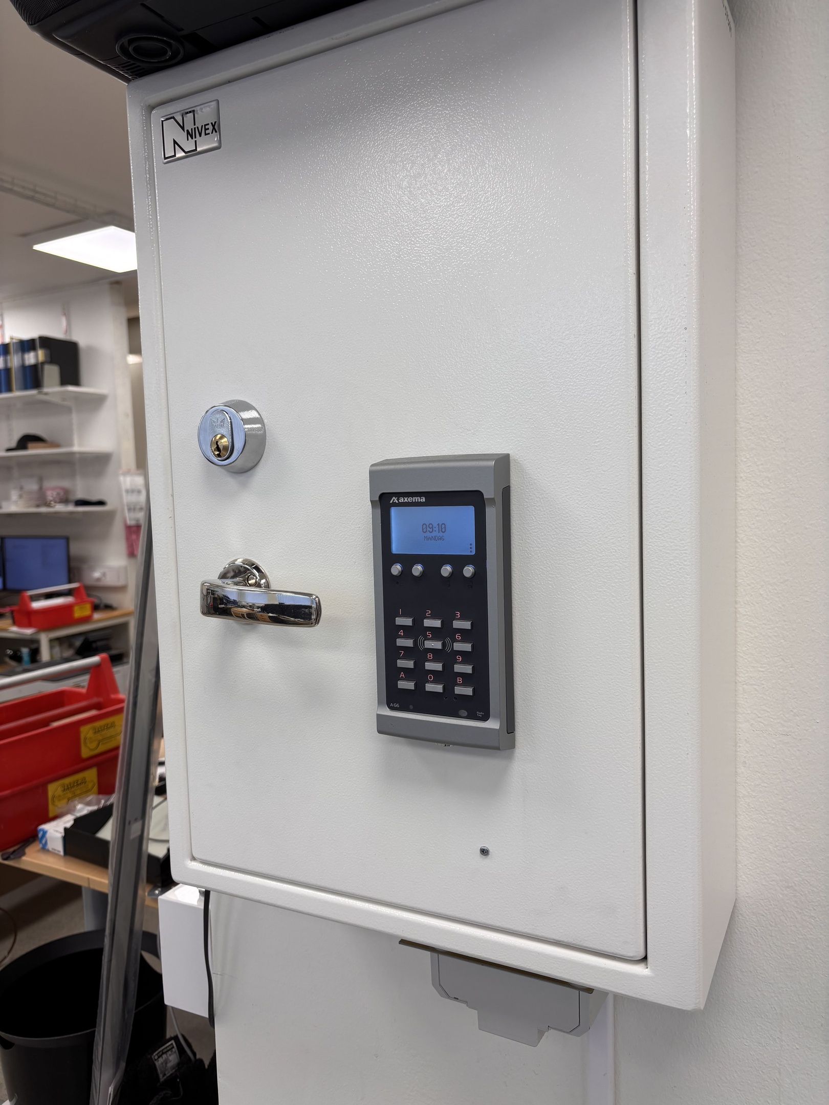 Person's hand engages with a digital keypad and intercom system on a textured wall, positioned beside an entrance door